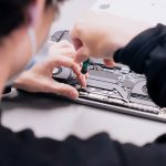 a woman is working on a laptop with her hands